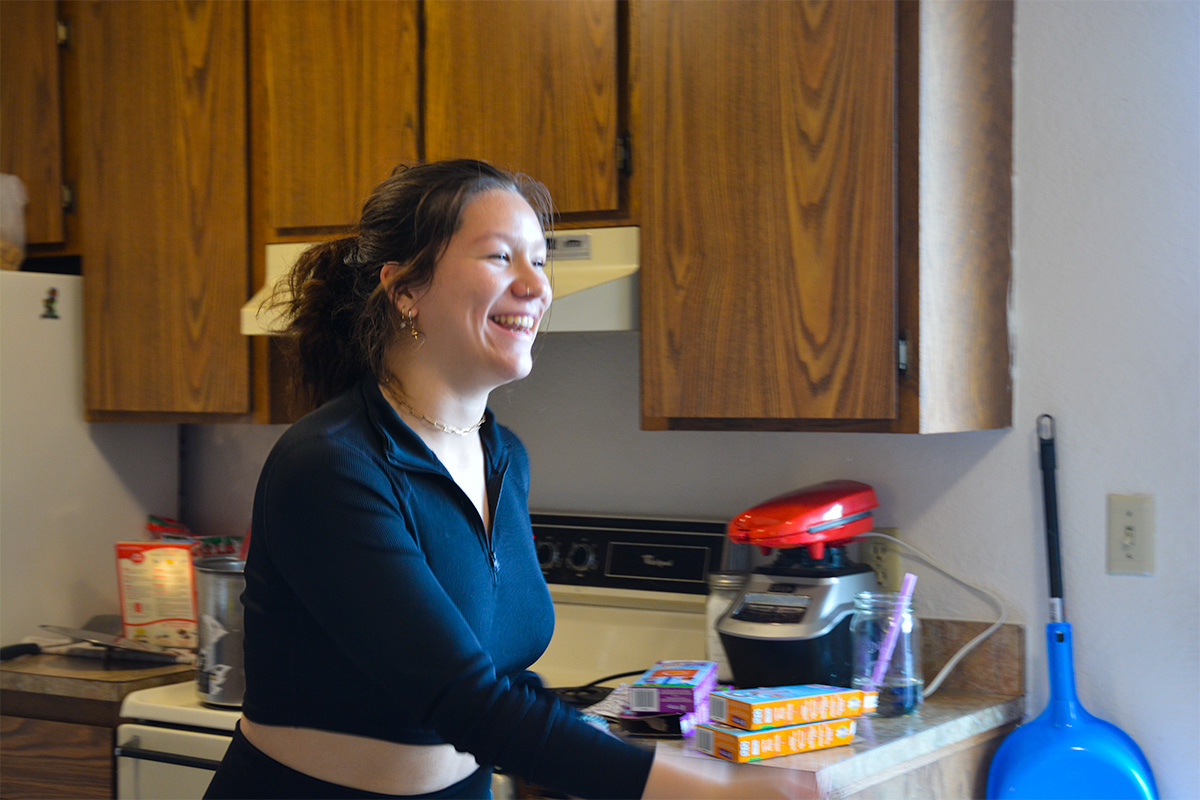 A woman in a black shirt moves across the room, a big smile on her face.